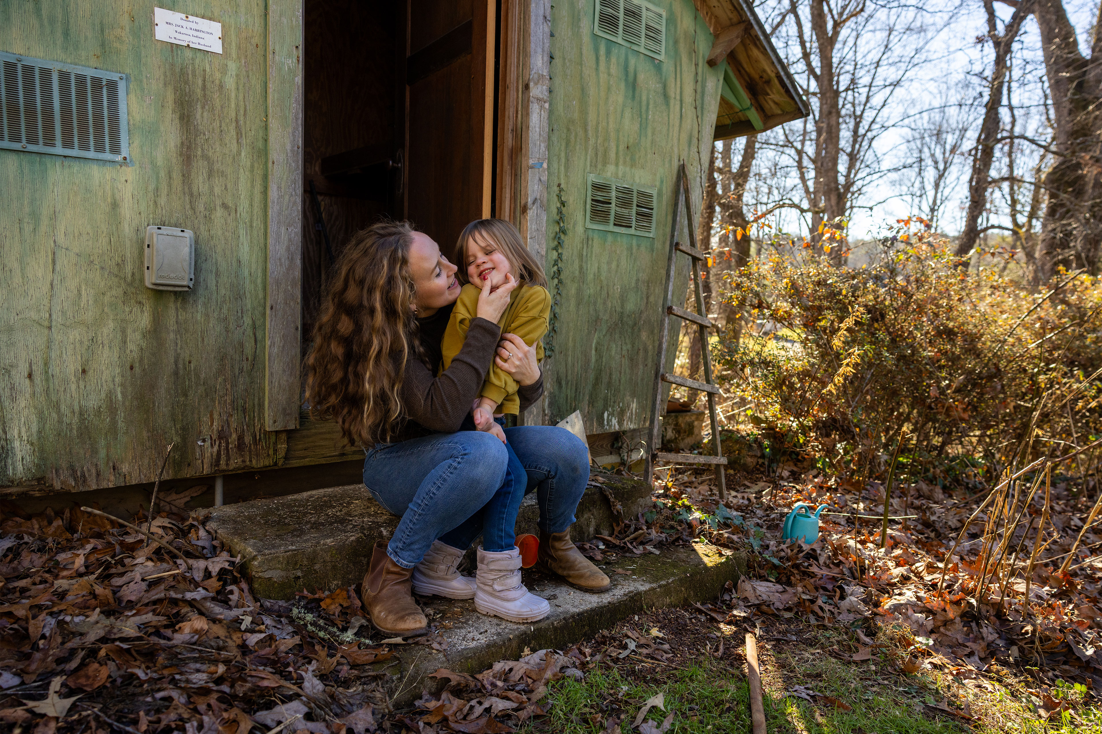 A photo of Kellyn Haight and her daughter sitting by a shed outside.